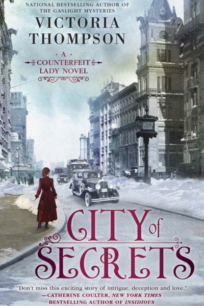 City of Secrets by Victoria Thompson book cover shows New York City street in the early 1900s. Snow is on the ground. An early car drives by, and a woman in red walks on the sidewalk.