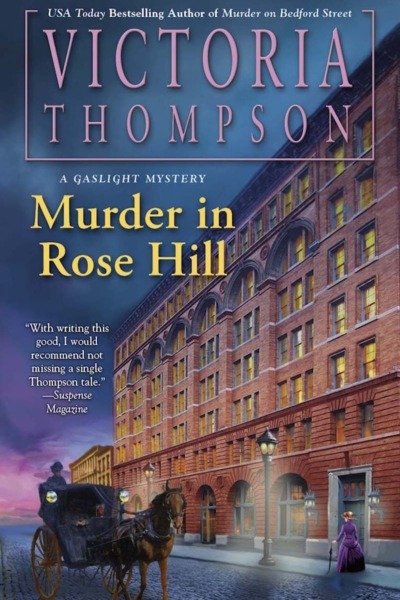 Murder in Rose Hill by Victoria Thompson book covershows the front of a brick building in New York City in the early 1900s. It's dusk and gas street lamps are lit. A woman in a purple dress with a cane walks by the building, and a horse and carriage passes by on the street.